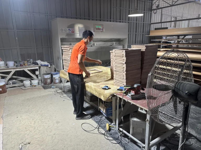 Worker organizing finished wood components at a furniture production station