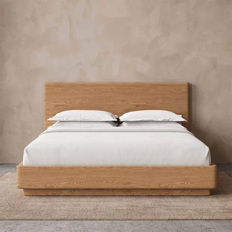 Light wood platform bed with a flat-panel headboard and rounded-edge frame in a plaster-walled room