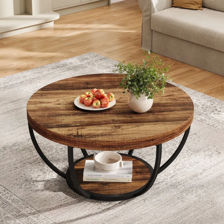 Round rustic brown coffee table with a plate of apples and a plant on top and a bowl on the lower shelf, seen from above