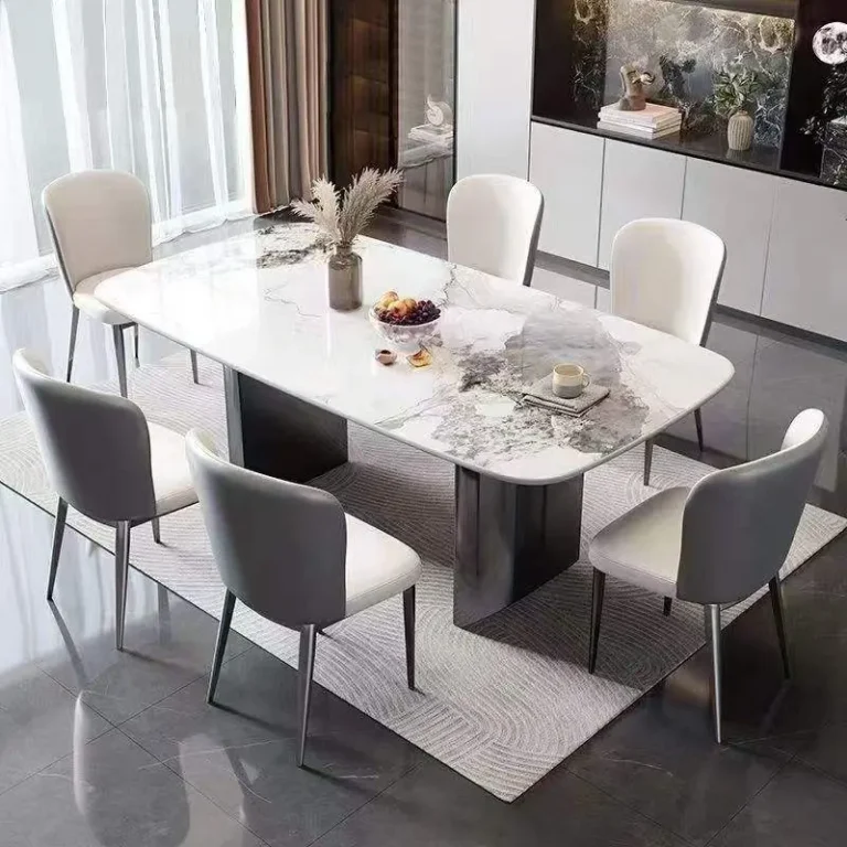 Rectangular white stone table with grey patterns, dark twin base and six chairs on a rug