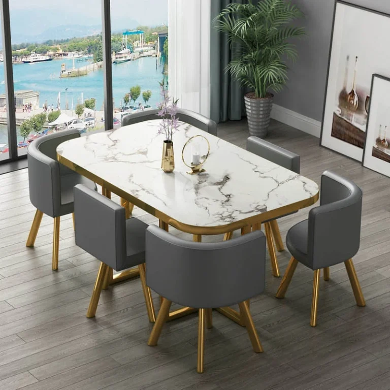 Rectangular white marble-look table with gold edge and gold legs and six grey chairs by a window