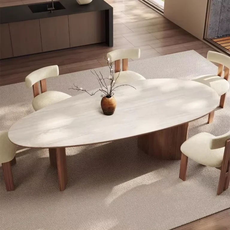 Egg-shaped oval stone-look table on a walnut-finish base with cream chairs, three-quarter view