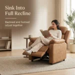 Woman reading in the cognac recliner with the footrest raised, captioned backrest and footrest adjust together