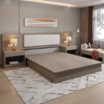 Taupe wood platform bed with a long headboard panel with cream padded insert, two nightstands and a bench by the window