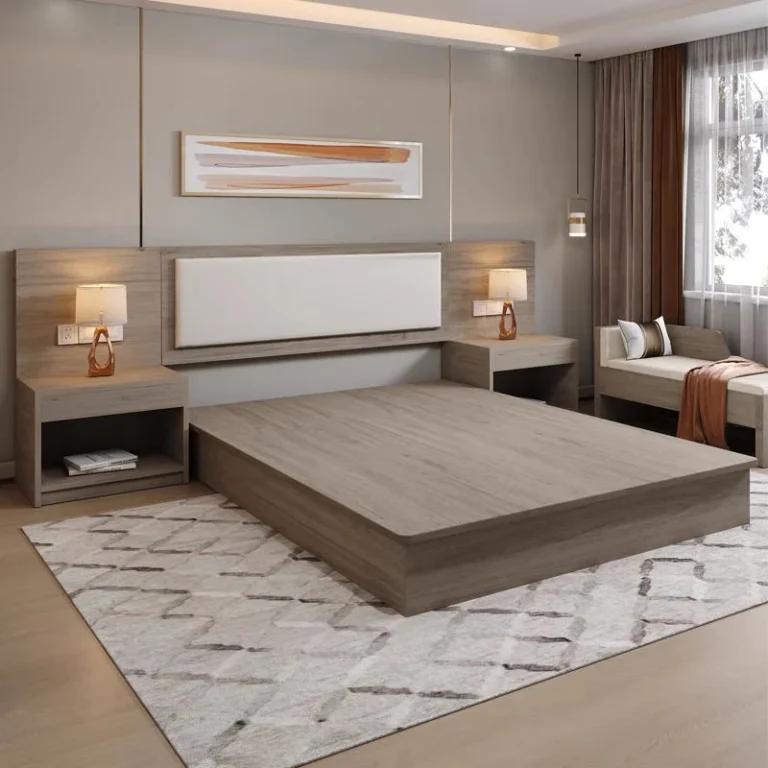 Taupe wood platform bed with a long headboard panel with cream padded insert, two nightstands and a bench by the window