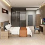 Room view with taupe wood bed, gray padded headboard, long desk with chair, wall-mounted TV and tall wardrobe