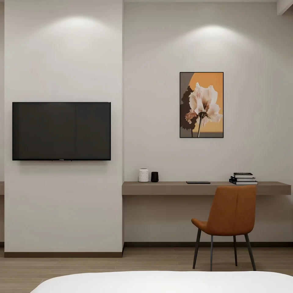 Wall-mounted TV above a long taupe wall-hung desk with a rust-colored chair and a framed picture