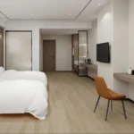 Wide room view with twin beds, a long wall-hung desk with chair and a wall-mounted TV