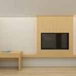 TV set into a wood-grain wall panel above a long light-oak desk ledge with a drawer unit at the left