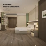 Hotel room from the door with the beige bed, sage-green accents, vanity and wardrobe area at the left