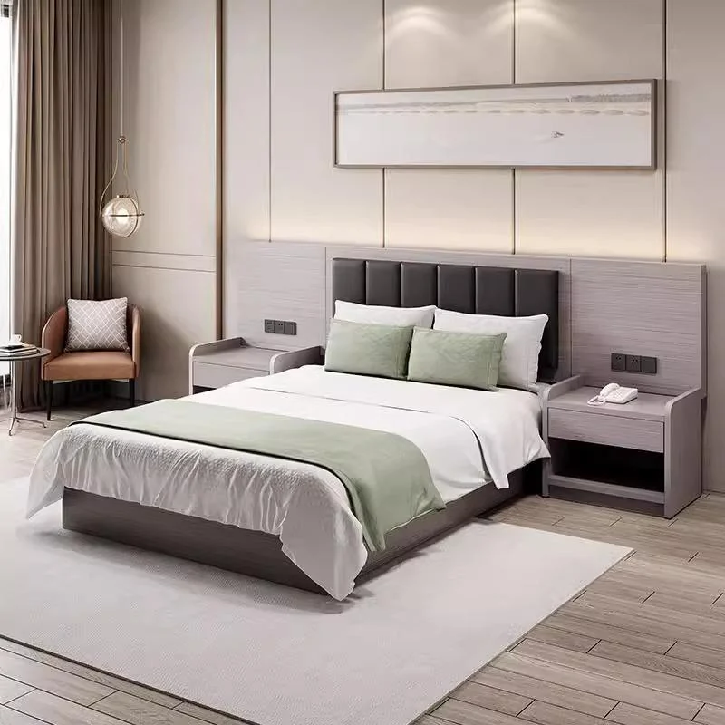 Bed with a charcoal padded headboard on a gray backboard, an open-shelf bedside table and an armchair, with a green throw