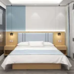 Made-up bed with a pale blue padded headboard on a light-oak backboard, two open-shelf nightstands and black pendant lights