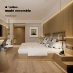 Twin beds from the foot with a round table and tablet in the foreground and the TV wall at the far end