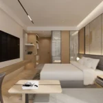 View toward the door with a low wood coffee table, the bed, a wall-mounted TV and an open wardrobe