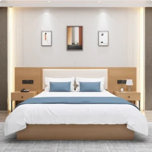 Made-up bed with a cream padded headboard, blue cushions and runner, and two one-drawer nightstands with phone and lamp