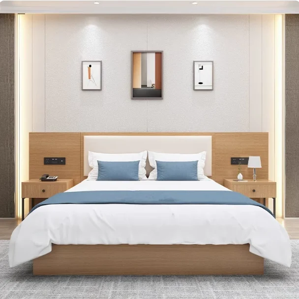 Made-up bed with a cream padded headboard, blue cushions and runner, and two one-drawer nightstands with phone and lamp