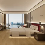 Dark-brown bed with a red padded headboard seen from the foot, with a dark nightstand and a chair at the window