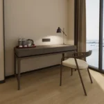 Dark gray-brown three-drawer desk with a kettle tray, a chair with a cream cushion and a desk lamp by a window