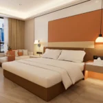 Bed from a low angle with the orange wall panel, a floating bedside shelf and a sofa at the window