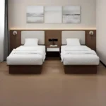 Twin beds with cream padded headboards, a white-topped nightstand with sockets between them and wall reading lights