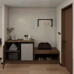 Entry area with a cabinet with a shelf of towels, a mini fridge and a safe, a bench with a shoe shelf and a clothes rail