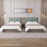 Twin layout with two made-up beds, mint-green headboards, a small nightstand between and ring pendant lights