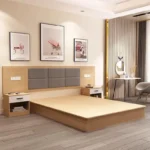 Light-wood platform bed base with a gray padded headboard, white-drawer nightstands and a dressing table by the wall