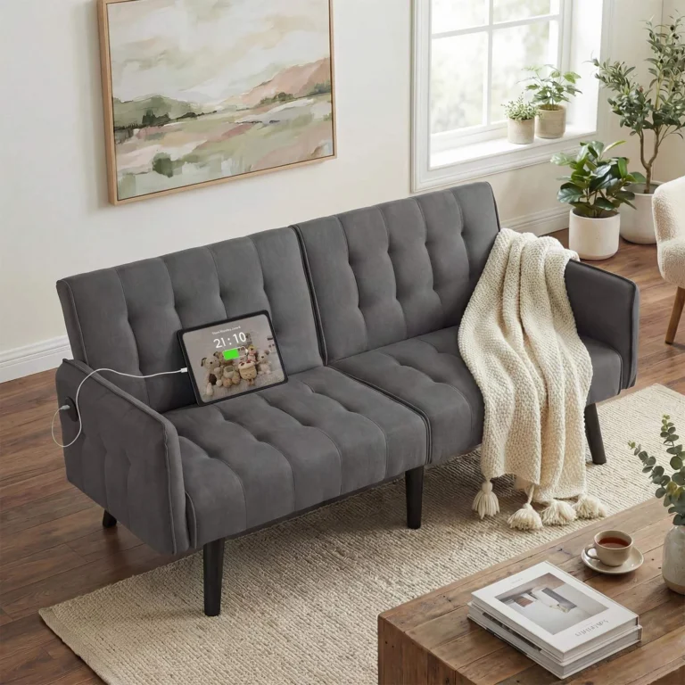 Dark gray tufted futon with a tablet charging from the arm in a living room