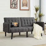 Gray tufted futon in a living room with a throw blanket