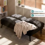 Black futon folded flat as a bed with a blanket