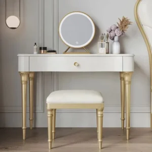 Cream vanity desk with turned gold-tone legs, a round LED mirror and a padded stool, in a paneled room