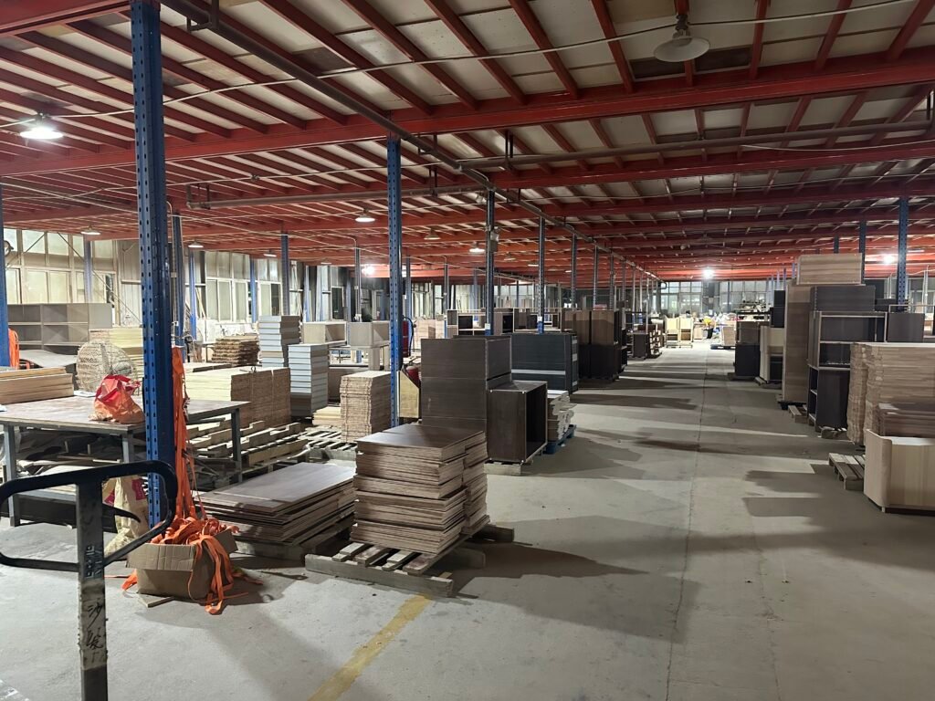 Cabinet carcasses, furniture panels and workbenches along the factory assembly aisle.