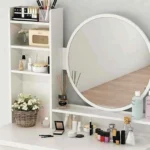 Close-up of the round mirror, the open shelf column and the ledge with cosmetics and a basket of flowers