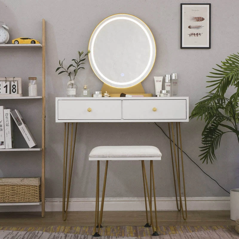 White slim vanity with a lit round LED mirror, two drawers, gold-tone hairpin legs and a padded stool, beside a ladder shelf