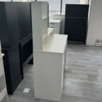 White vanity desk seen from the side, showing the open shelves and the cabinet door