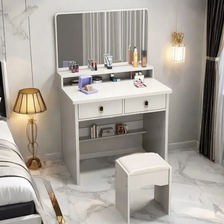 White compact vanity with a rectangular mirror, two drawers, a lower shelf and a white padded stool, on a marble-look floor