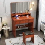 Wood-grain vanity with a rectangular mirror, two drawers, a lower shelf with books and a stool with a black padded seat