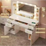 Vanity with callouts for open shelves, makeup trays, drawers and large cabinets, and a phone charging on the desk