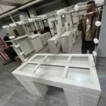 White vanity with the glass-covered compartment top and a bulb mirror, in a workshop