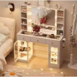 Vanity with warm-lit glass-front cabinets, a bulb mirror and a hairdryer on the side holder, in a bedroom