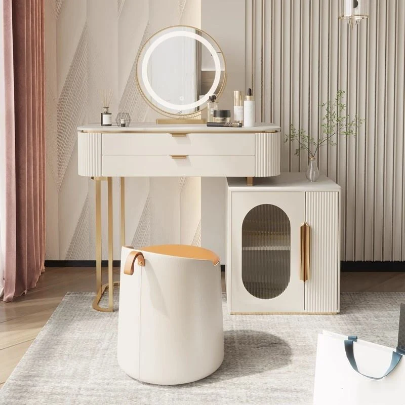 Cream vanity desk with a round LED mirror, a side cabinet with an oval window and a cylinder stool, in front of a fluted wall