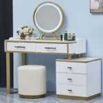 White fluted vanity with a gold-framed round LED mirror, a three-drawer cabinet and a cream fluted stool, by a blue wall