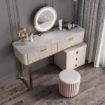 Cream-white vanity from an angle, with a marble-look top, two drawers, the cabinet and a pink fluted stool