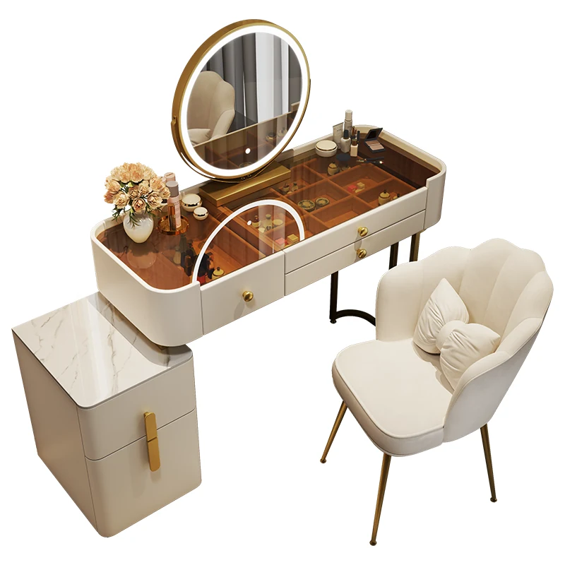 Cream vanity on a white background with a tinted glass top, a round LED mirror, a two-drawer cabinet and a scalloped chair