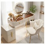 Cream vanity with an amber glass top, a round LED mirror and a scalloped chair, in a bright room with a plant